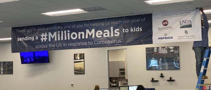 A commemorative banner is hung at McLane Global headquarters during the first week of the collaborative goal with the U.S. Department of Agriculture (USDA), PepsiCo, and Baylor Collaborative on Hunger and Poverty to deliver nearly 1,000,000 meals per week to students in a limited number of rural schools closed due to COVID-19, Houston, Texas, on March 26, 2020. (USDA Photo by Lance Cheung.)